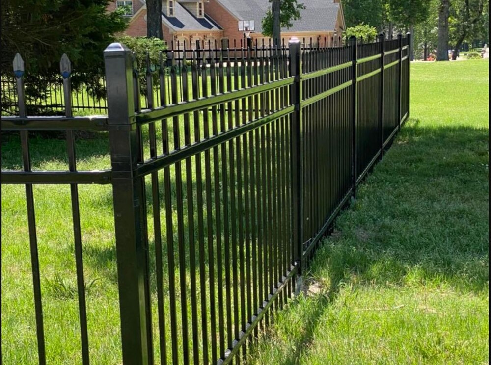 Completed black ornamental metal fence bordering a landscaped residential yard