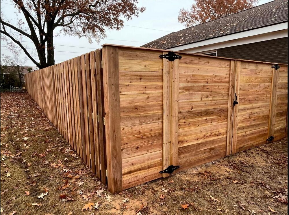 Completed cedar privacy fence and gate beside a home